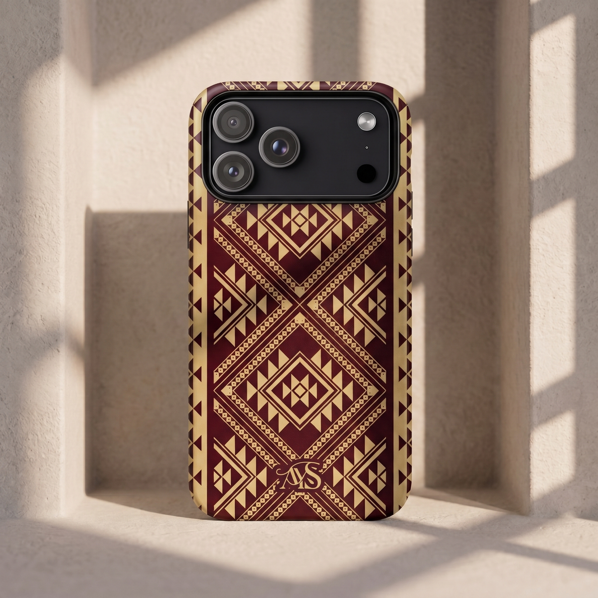 Burgundy Rose geometric tough phone case resting against a wall with warm sunlight casting square shadows through a window